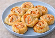 Girelle di pasta sfoglia con salmone affumicato e mozzarella dorate al forno, servite su piatto blu