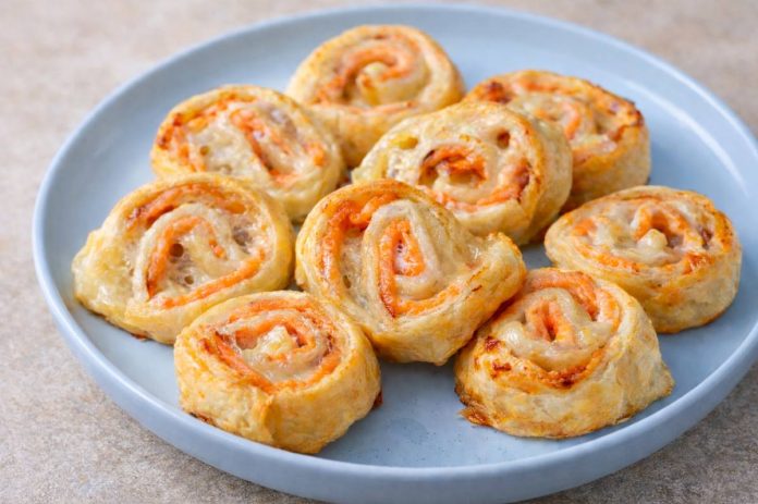 Girelle di pasta sfoglia con salmone affumicato e mozzarella dorate al forno, servite su piatto blu